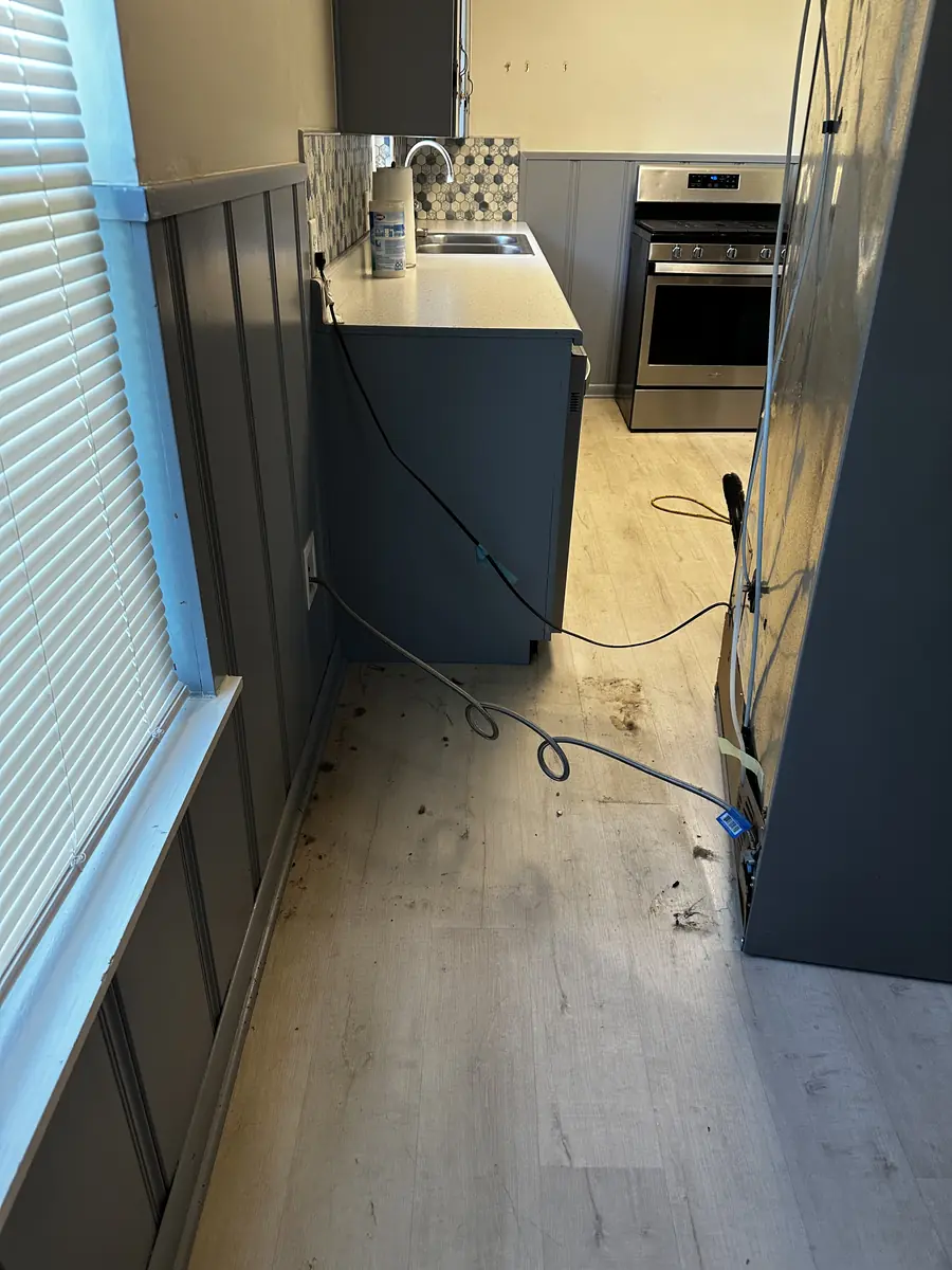 Dirty floor and debris where the refrigerator stood, before a move-out clean