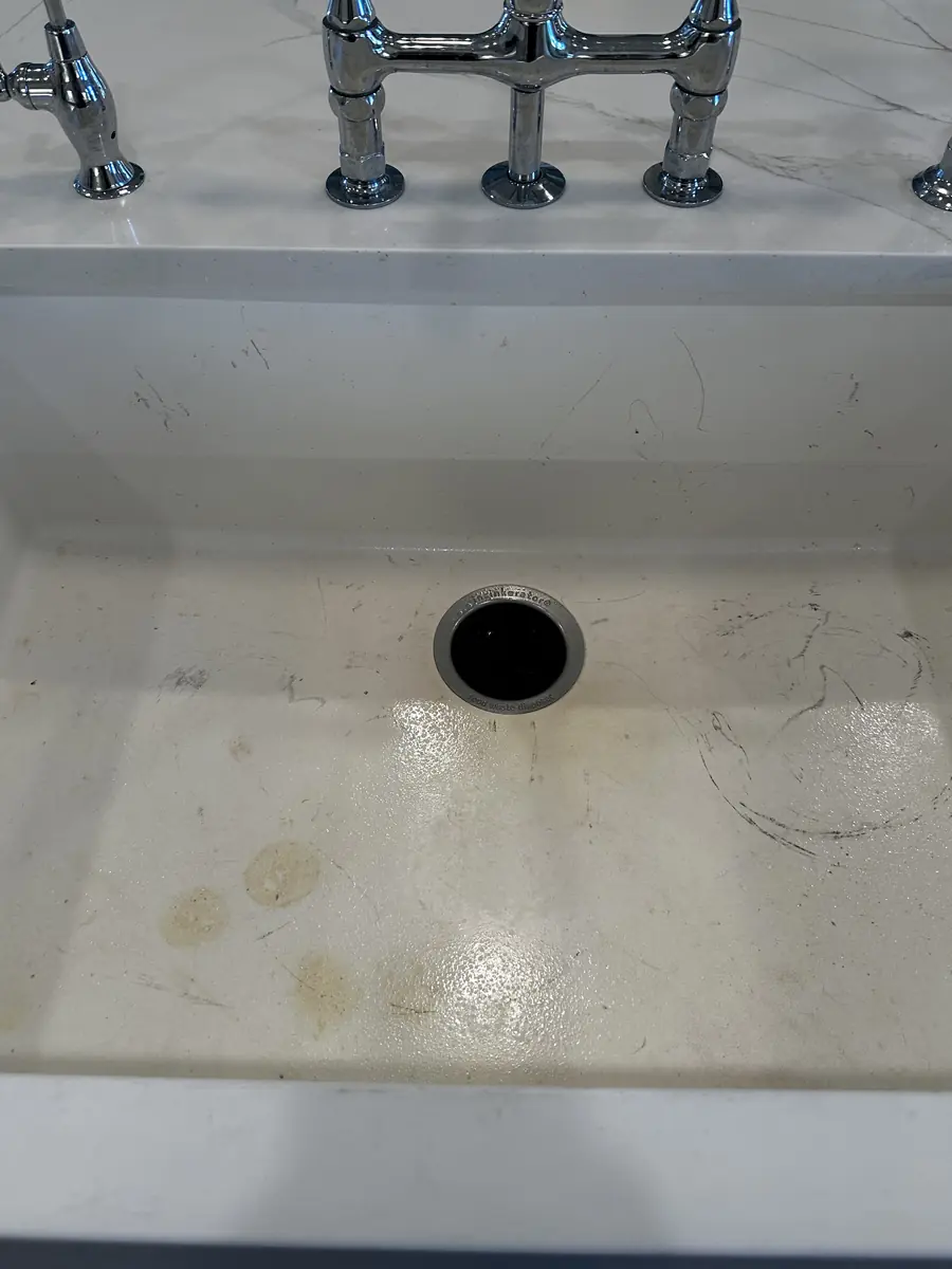 Porcelain farmhouse sink with stains and marks, before
