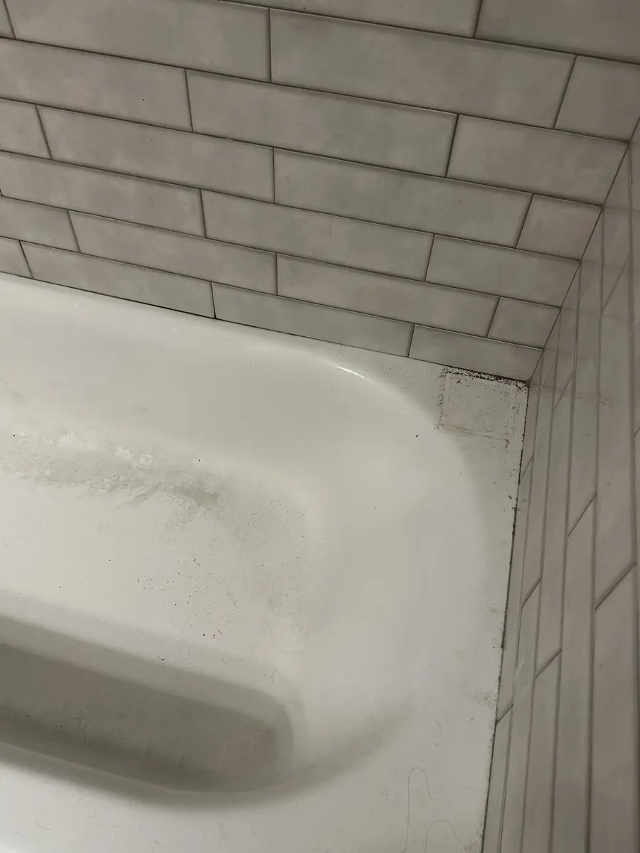 Bathtub with soap scum and a dirty tile corner, before